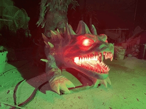 Glowing animatronic dragon head prop with red eyes and sharp teeth