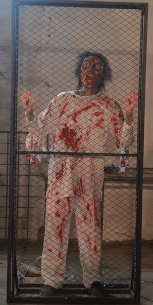 cyclops zombie animatronic banging on metal fence inside haunted room