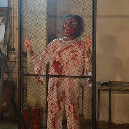 cyclops zombie animatronic banging on metal fence inside haunted room