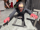 Crawling animatronic demon with red hands on rail track in haunted house scene