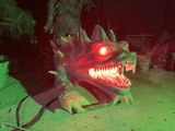 Glowing animatronic dragon head prop with red eyes and sharp teeth
