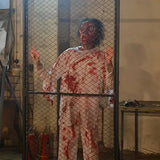 cyclops zombie animatronic banging on metal fence inside haunted room