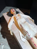 Animatronic psychiatric patient in yellow gown twisting on hospital bed for haunted attraction