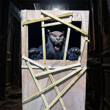 animatronic werewolf monster roaring through broken wooden wall in haunted house